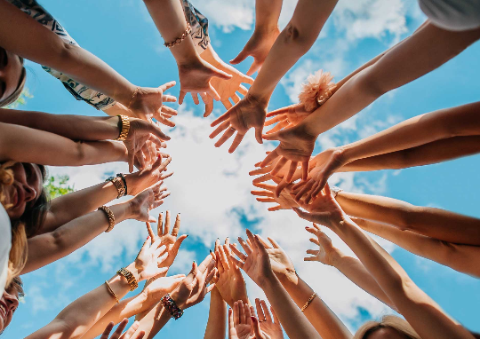 Imagen de un grupo de personas levantando sus manos